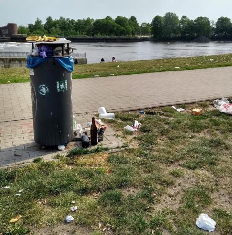 Überfüllter Mülleimer am Ufer der Weser. Herausgefallener Müll liegt daneben.